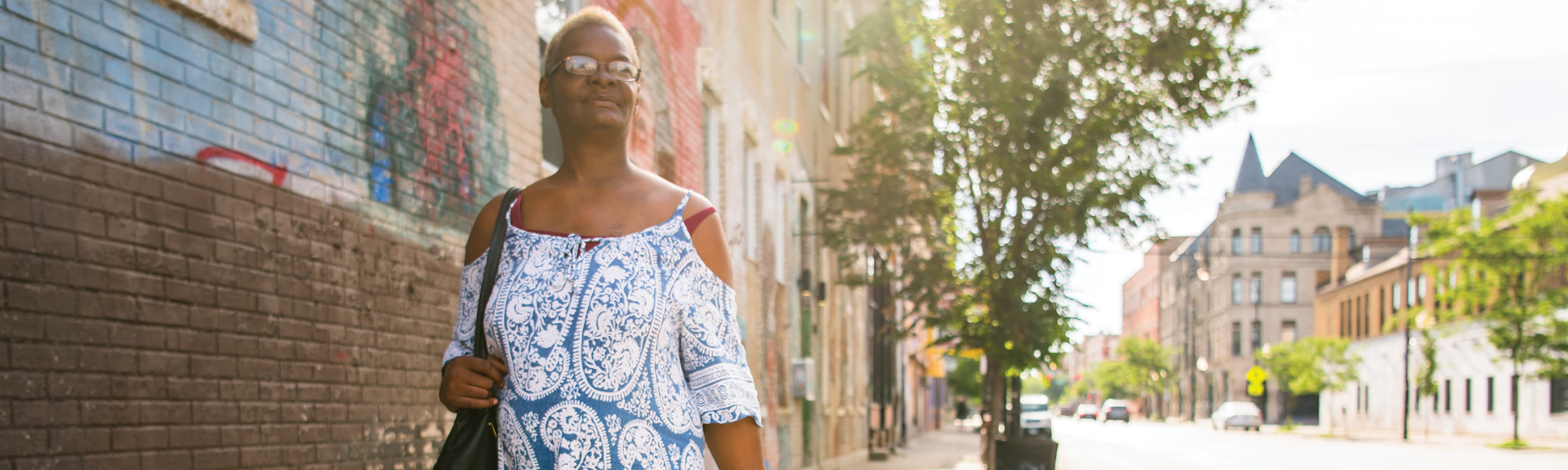 woman in glasses walking down city street looking off into the distance
